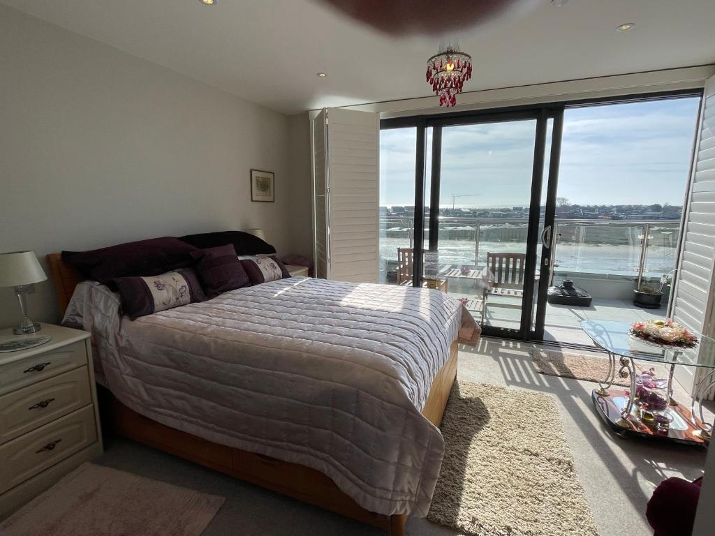 a bedroom with a large bed and a large window at Special Occasion, Stunning sea view balconied suite in Shoreham-by-Sea
