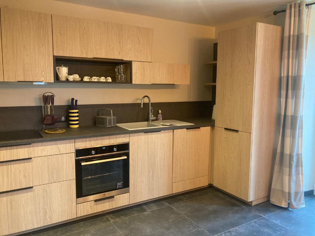 a kitchen with wooden cabinets and a sink at Le Goulet in Prémanon