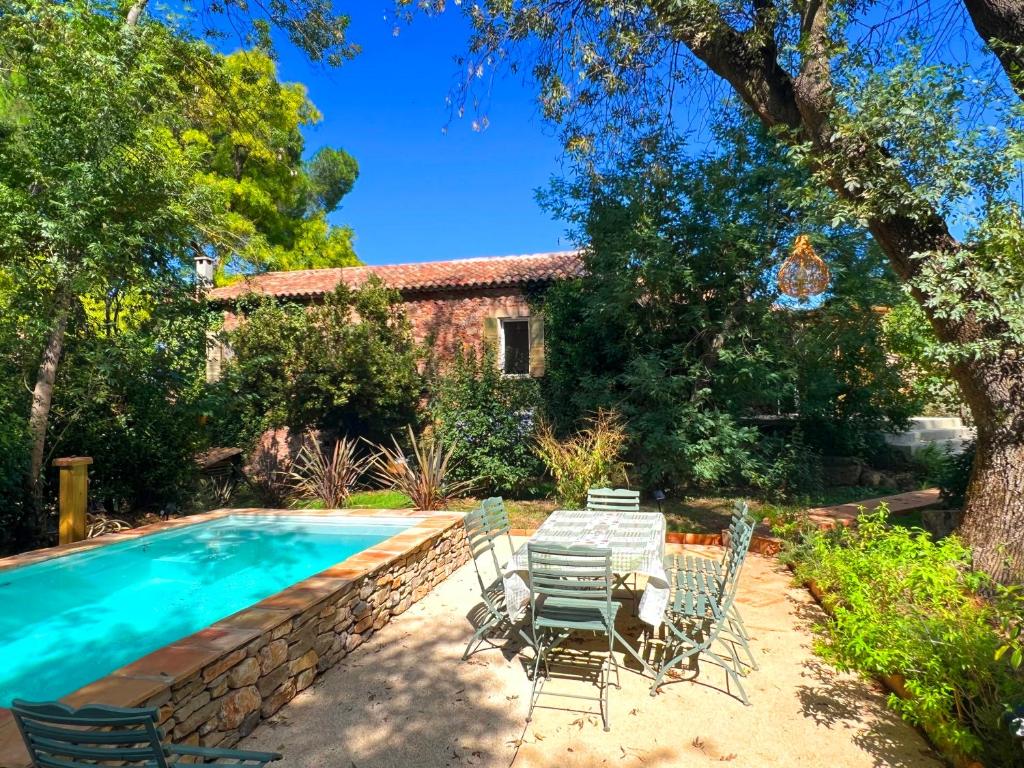 a pool with chairs and a table next to a house at Maison en pierre rénovée avec jardin et piscine privative chauffée in Hyères