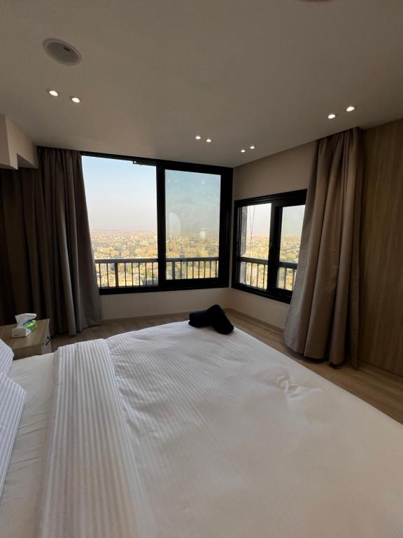 a bedroom with a large white bed with large windows at Lumen Residence in Cairo