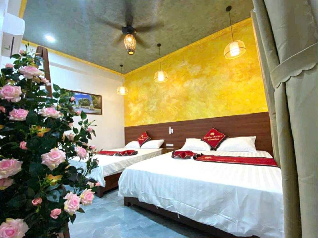 a hotel room with two beds and flowers at Tam Coc HaVi's Hotel - Restaurant in Văn Lâm