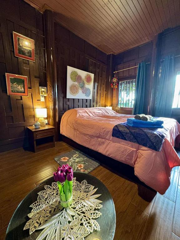 a bedroom with a bed and a table with flowers on it at Thai Classic House Rimtalay in Ban Rong Po