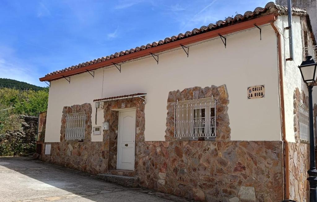 a stone building with a white door and a window at Casa de piedra en el Valle de Lozoya in Canencia
