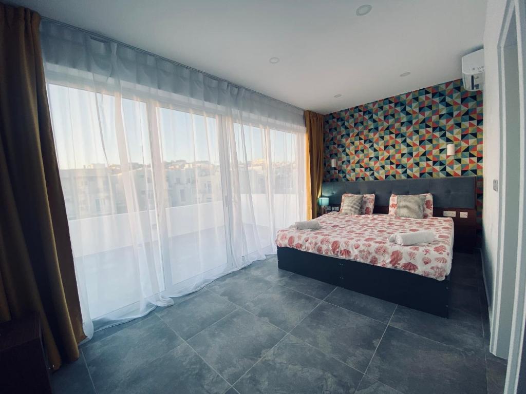 a bedroom with a bed and large windows at Dar One - Self catering & self check in apartments by Tritoni Hotels in Il-Gżira