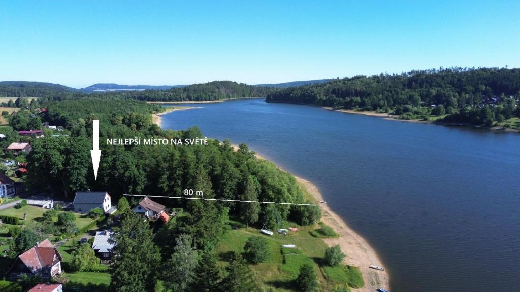 a view of a river with a house on a island at Apartmánová chata u pláže Sečské přehrady in Hoješín