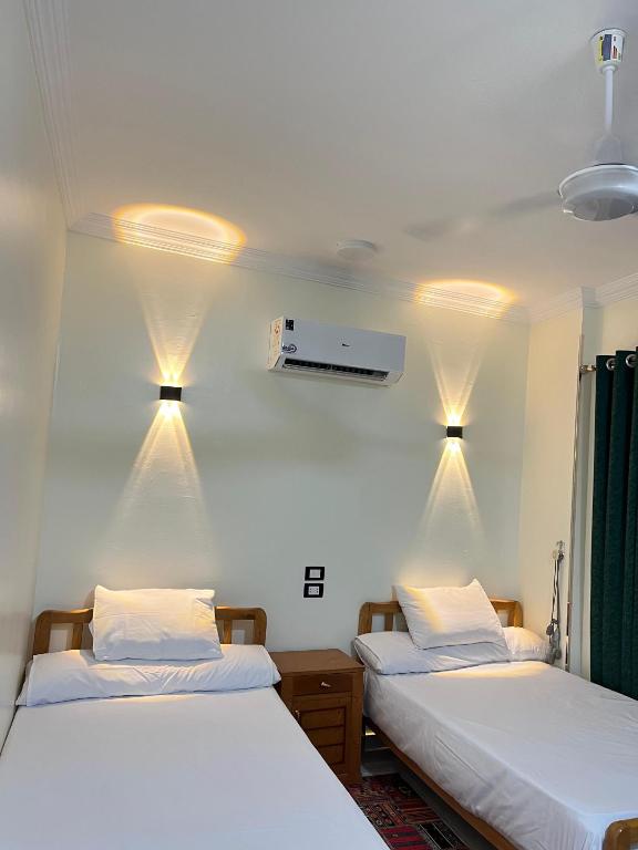 two beds in a room with lights on the wall at Mayor Nubian guest house in Aswan