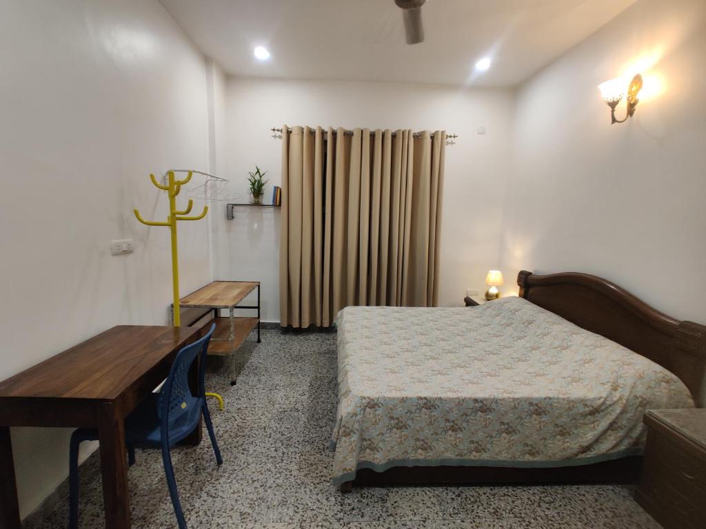 a bedroom with a bed and a table and a desk at Vedica Vatica in Shivpuri