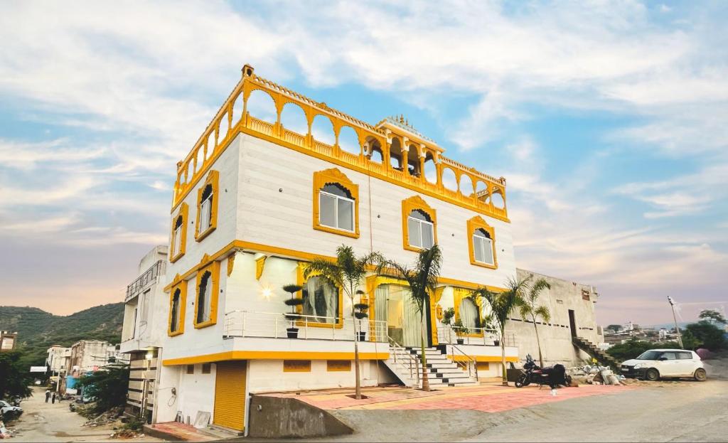 ein weiß-gelbes Gebäude mit Palmen davor in der Unterkunft Jai Pushkara Luxe Stay -Luxury Heritage Hotel in Pushkar