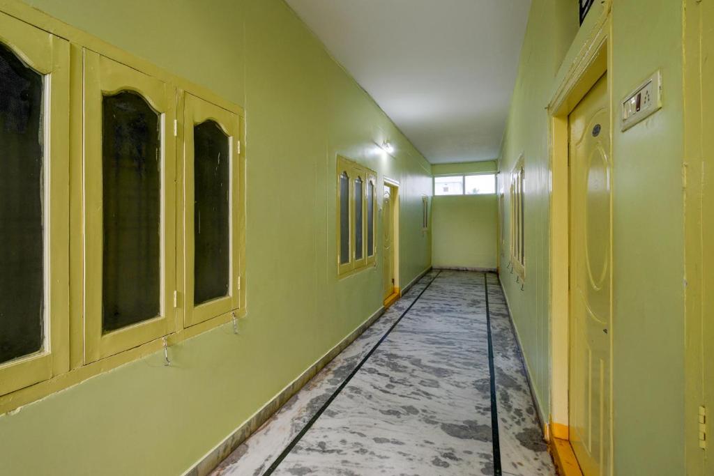 een lege gang met groene muren en ramen bij SPOT ON Harshitha Guest House in Pedda Ambarpet