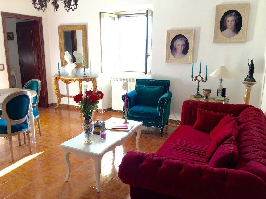 un soggiorno con divano rosso e sedie blu di Medieval Cosy Getaway a Giuliano di Roma
