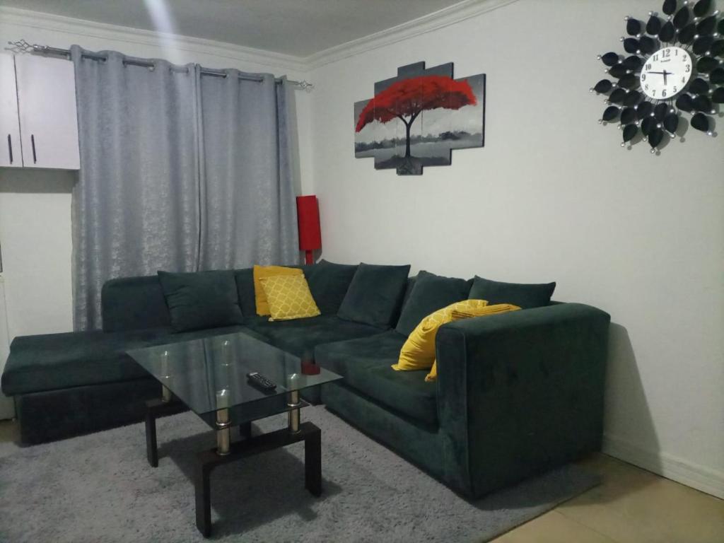 Una sala de estar con un sofá verde y una mesa de cristal. en The Karen Haven, en Nairobi