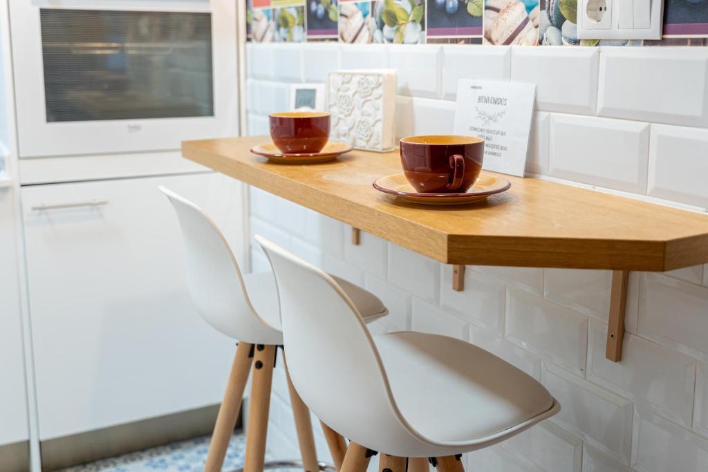 Dos tazas en una mesa de madera con dos sillas. en La casita de Lola by urbanhosting, en Santander