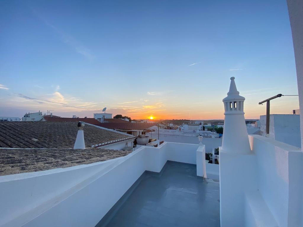 ein Sonnenuntergang auf dem Dach eines Gebäudes mit einem Leuchtturm in der Unterkunft A Casa da Velha in Alvor