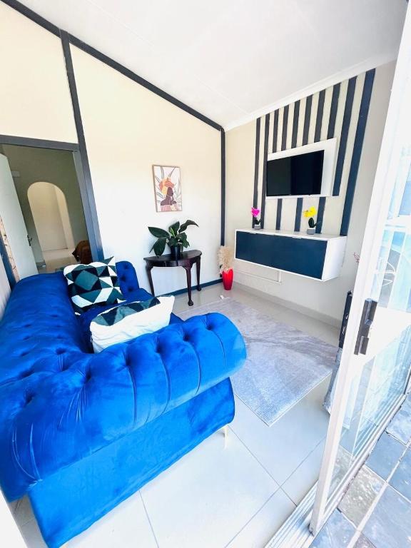 eine blaue Couch in einem Wohnzimmer mit einem Fernseher in der Unterkunft Enez Place in Gqeberha