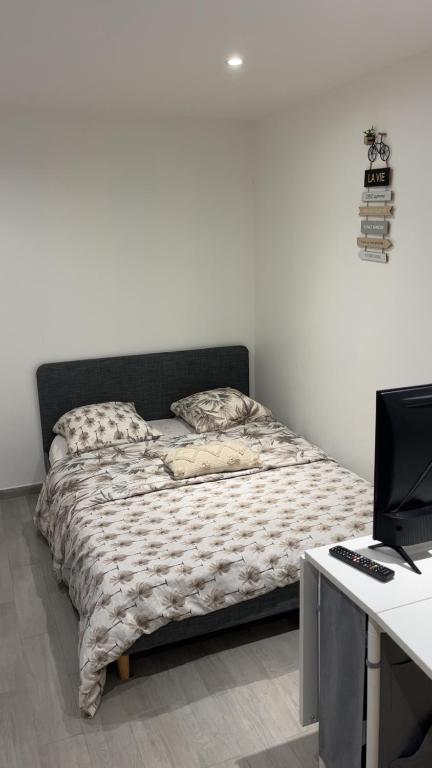 a bed in a room with a desk and a computer at Studio neuf avec terrasse et entrée indépendante in Élancourt