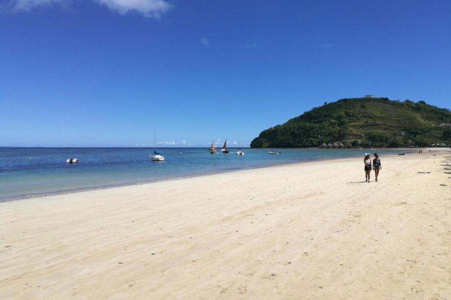 twee mensen lopen op een strand bij het water bij VILLA AMNESYA NOSY BE in Nosy Be
