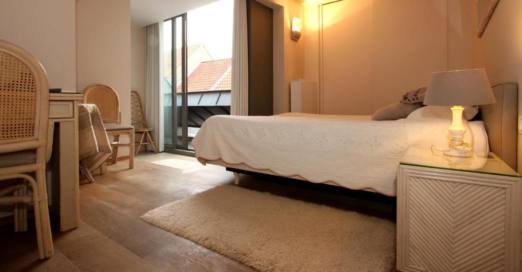 a bedroom with a bed and a table with a lamp at B&B 't Walleke in Bruges