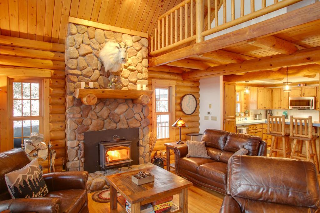 a living room with leather furniture and a stone fireplace at Rustic Gotham Bay Cabin on Lake Coeur dAlene in Harrison