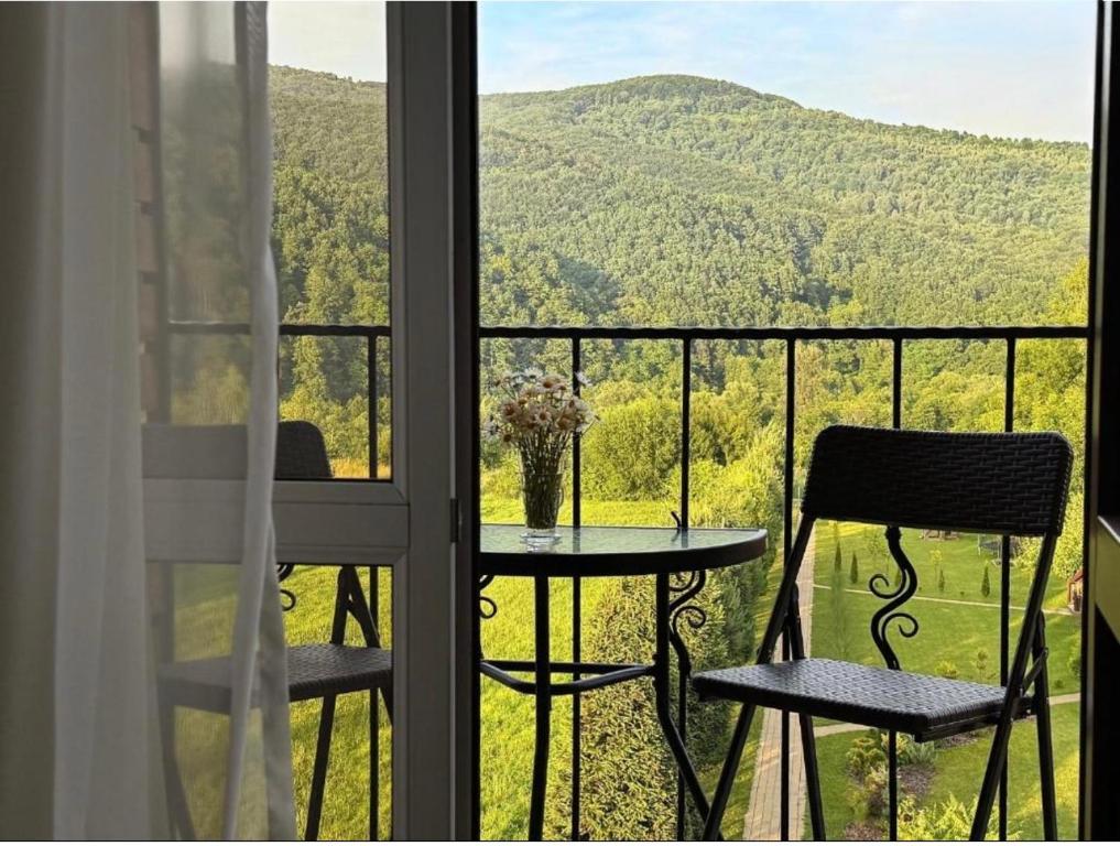 a balcony with a table and chairs and a view of a mountain at Садиба в ГОРАХ in Solochin