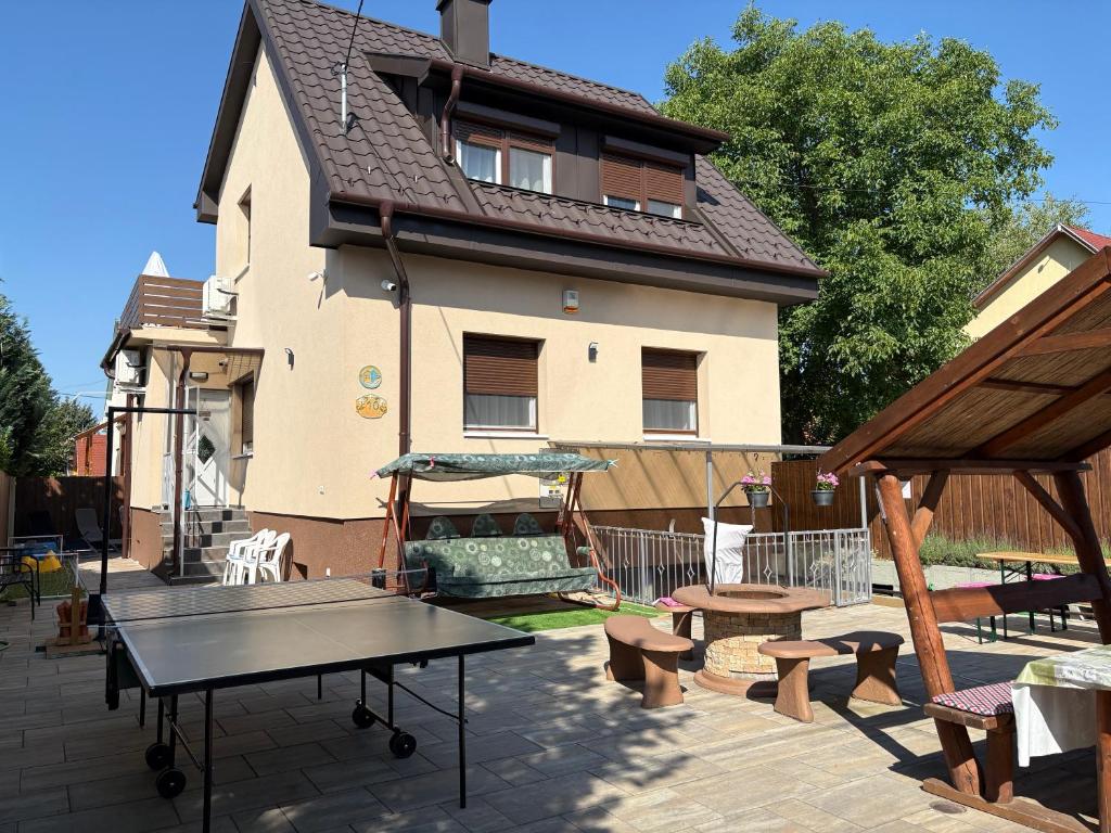 a ping pong table and benches in front of a house at Silver Zsóry Apartman II. in Mezőkövesd