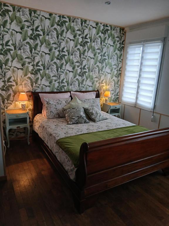 a bedroom with a bed with a floral wallpaper at Les 4 Portes in Le Mesnillard
