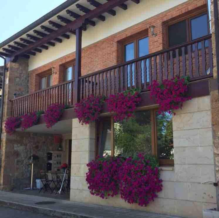 a building with purple flowers on the balcony at Casa pareada rural Elechino in Entrambasaguas