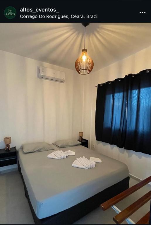 a bedroom with a large bed with a chandelier at Da terra Altos in Aracati