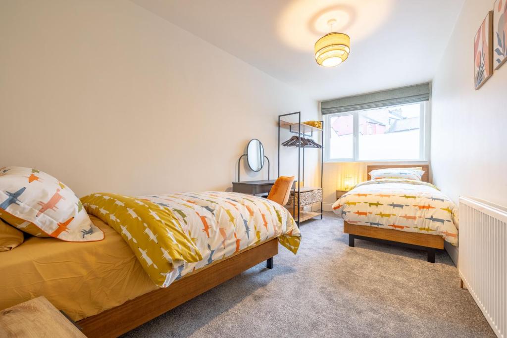 a bedroom with two beds and a window at Battersea Boutique Apartments in Bangor