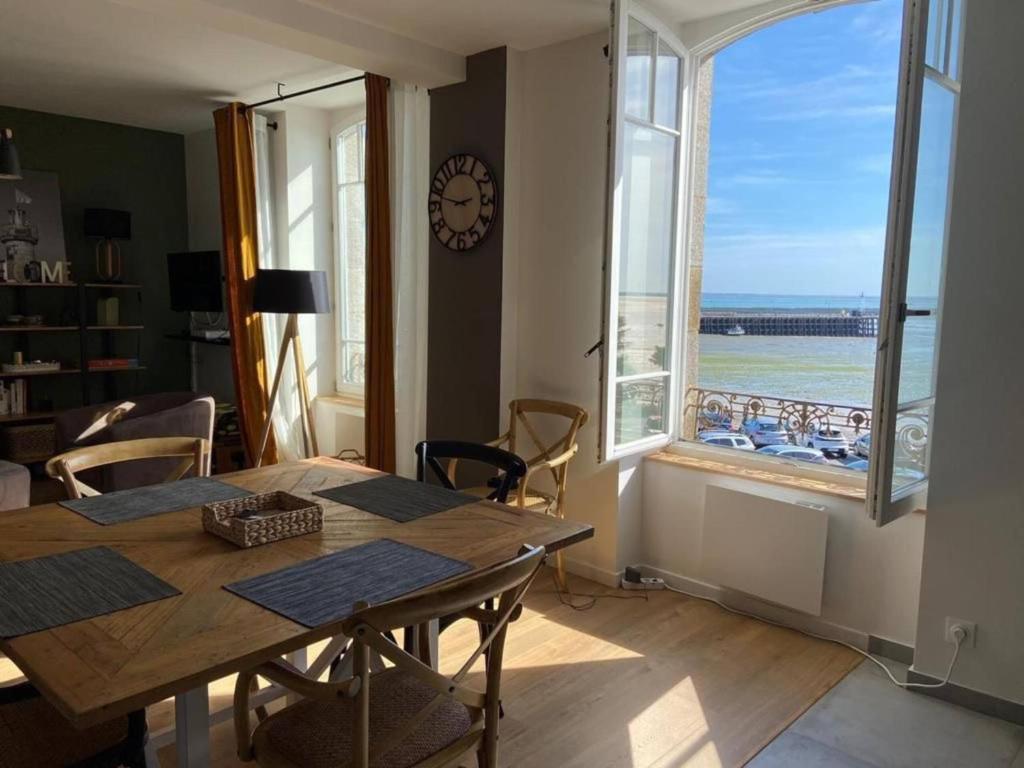 a dining room with a table and a large window at Cancale, vue mer, accès direct sur la baie du Mont-Saint-Michel in Cancale