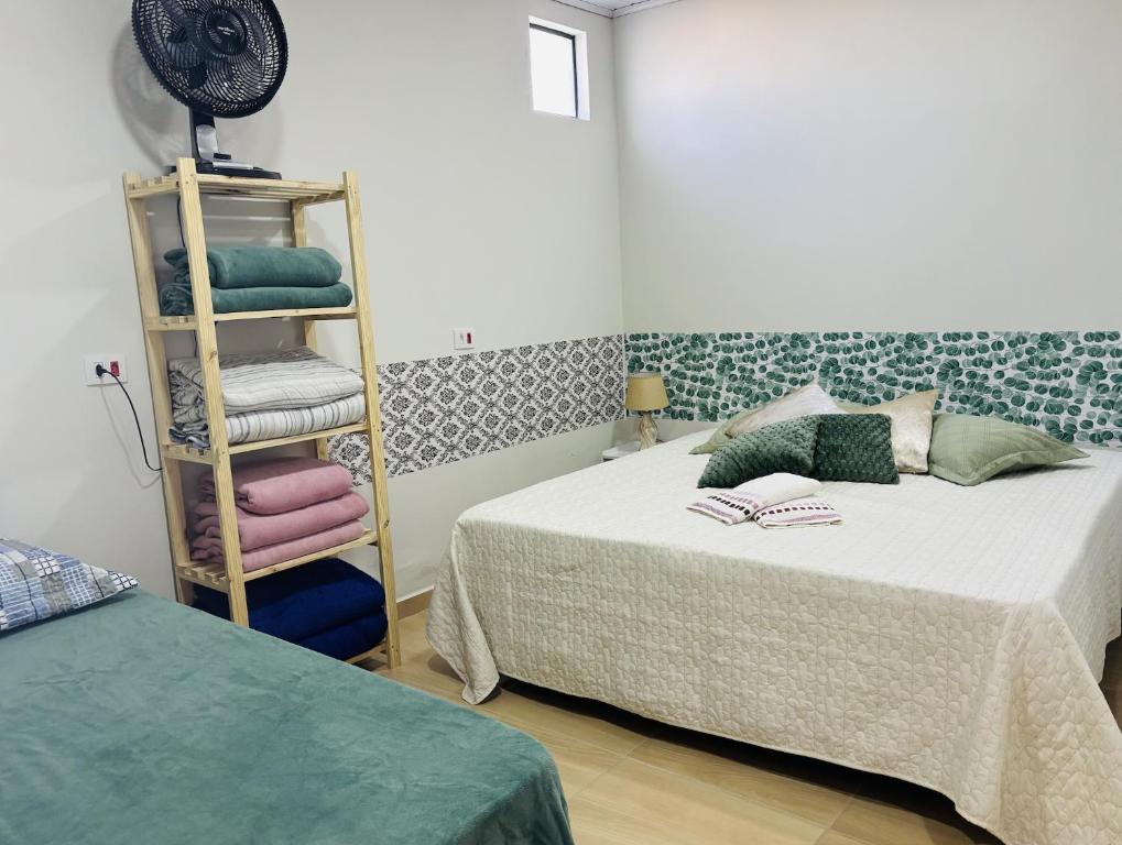 a bedroom with two beds and a shelf with towels at Rancho do Viajante APARTAMENTO B in Castro