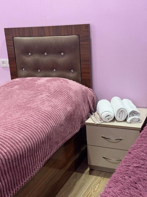 a bedroom with a bed and a night stand with towels at AlexMila in Tatʼev
