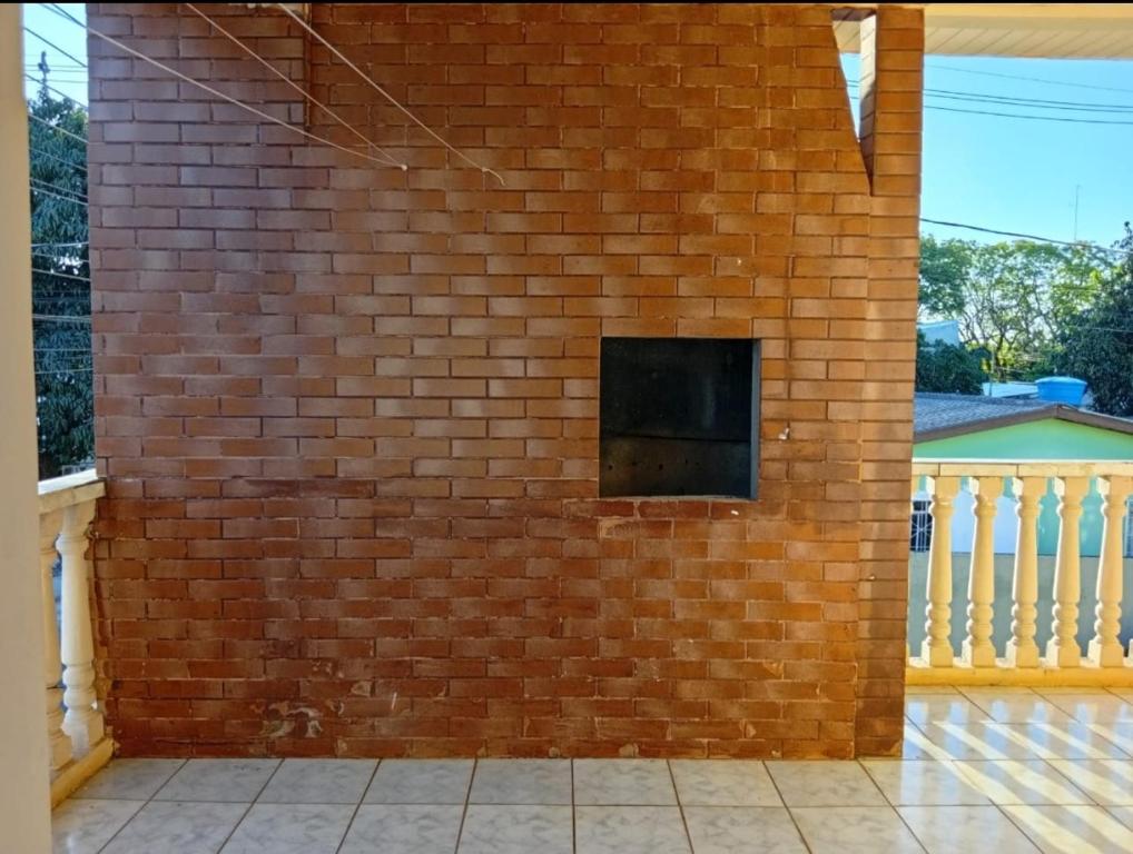 eine Ziegelwand mit einem kleinen Fenster in der Unterkunft Casa ampla e aconchegante in Foz do Iguaçu