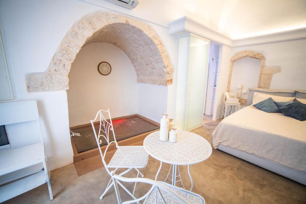 a bedroom with a bed and a table and chairs at Nivèra White Allure Maison in Ostuni