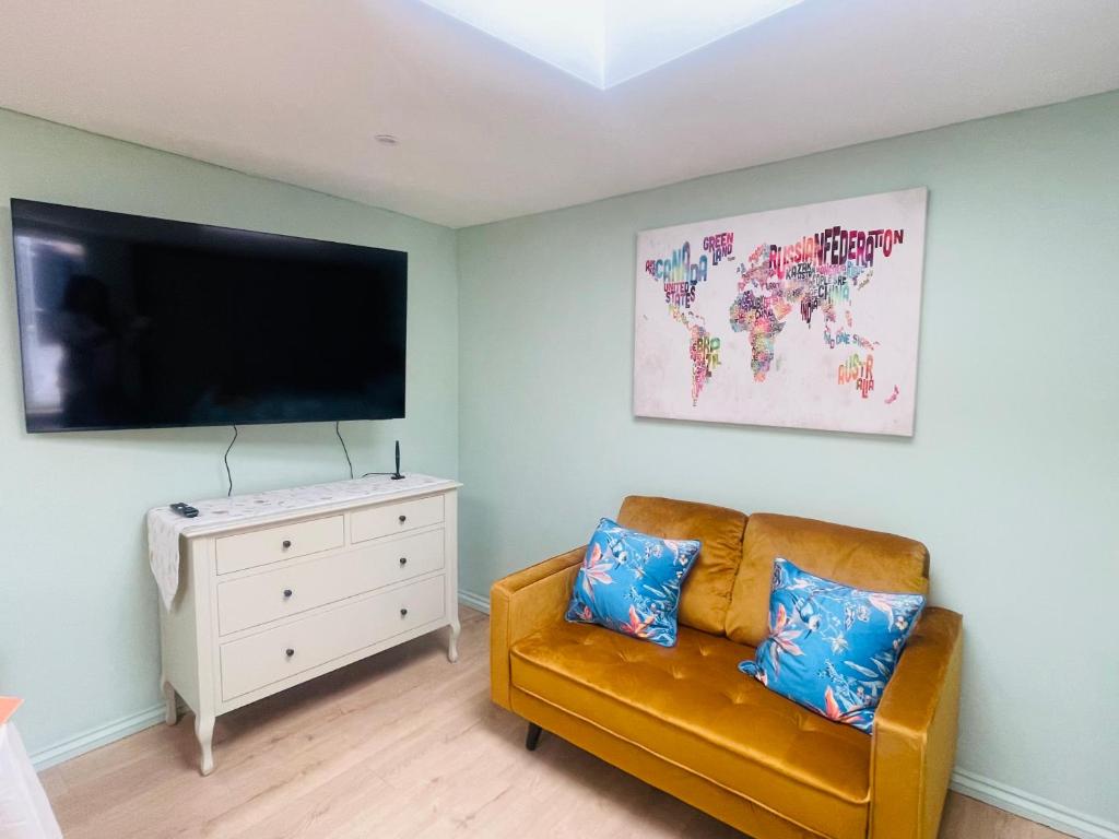 een woonkamer met een bank en een flatscreen-tv bij Newly refurbished spacious studio flat in Wimbledon in Raynes Park