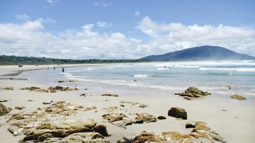 a beach with rocks and people in the water at Oceanique in Old Bar