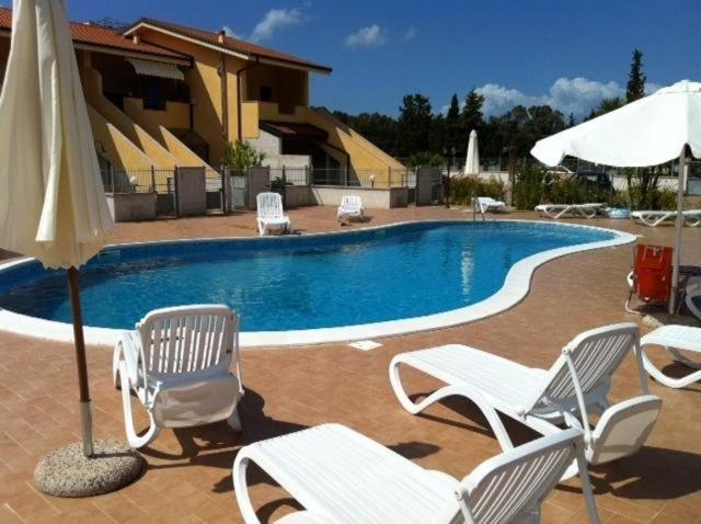 ein Swimmingpool mit Stühlen und einem Sonnenschirm in der Unterkunft Appartamento Carnovale WiFi Piscina divertimento sul mare di Pizzo in Fondaco Vecchio