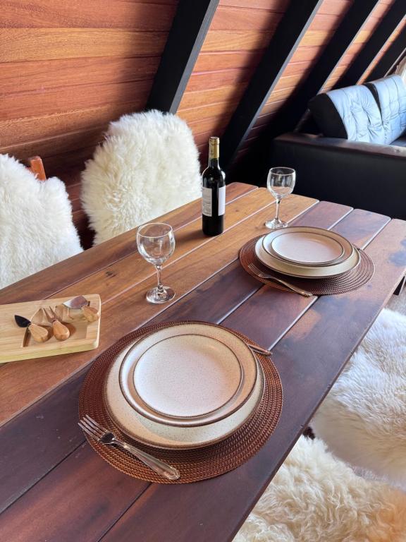 a table with plates and glasses and a bottle of wine at Cabana Catuaí in Espera Feliz