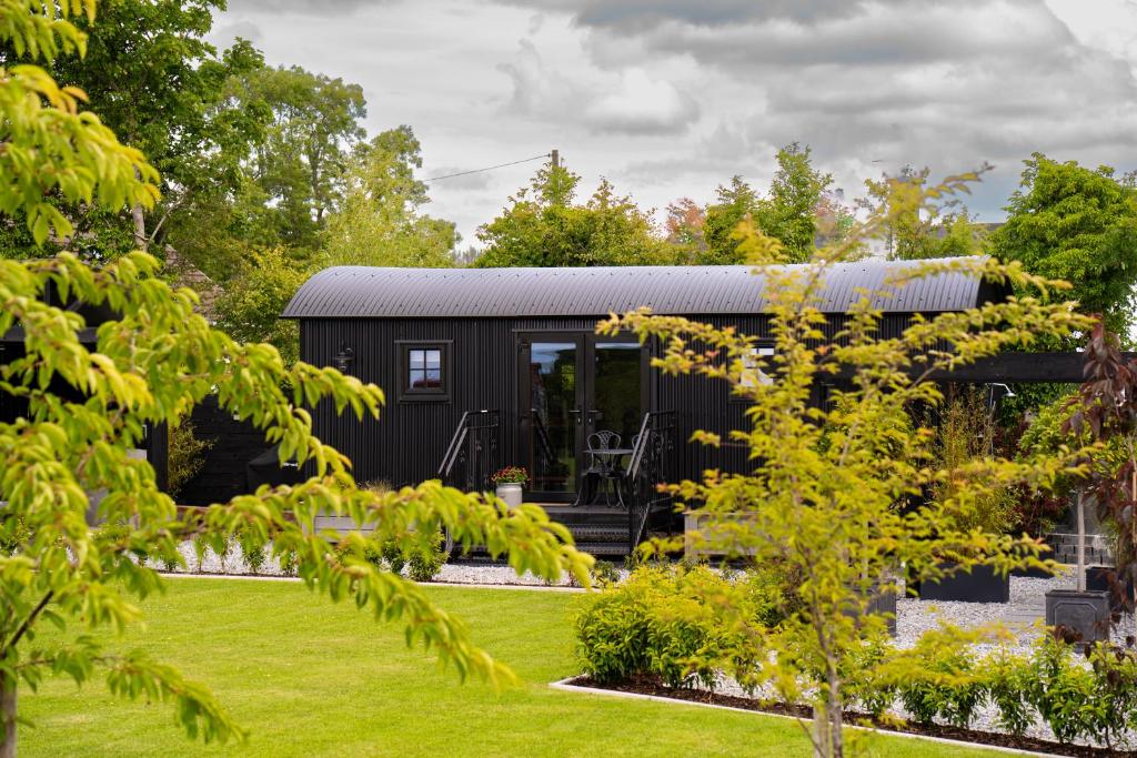a black tiny house in a garden at Cherry Tree Lodge in Limavady