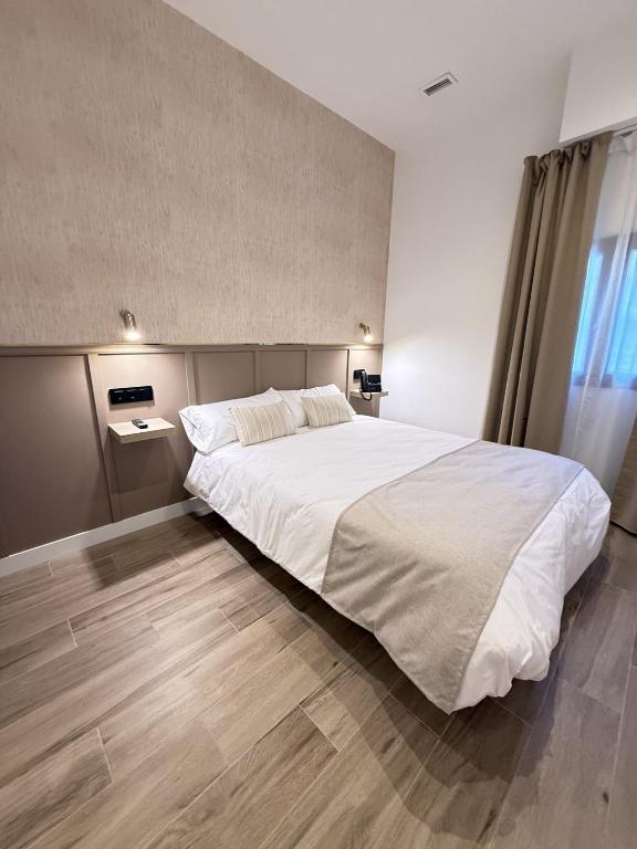 a bedroom with a large white bed and a wooden floor at Be RELAX TORREJON in Torrejón de Ardoz