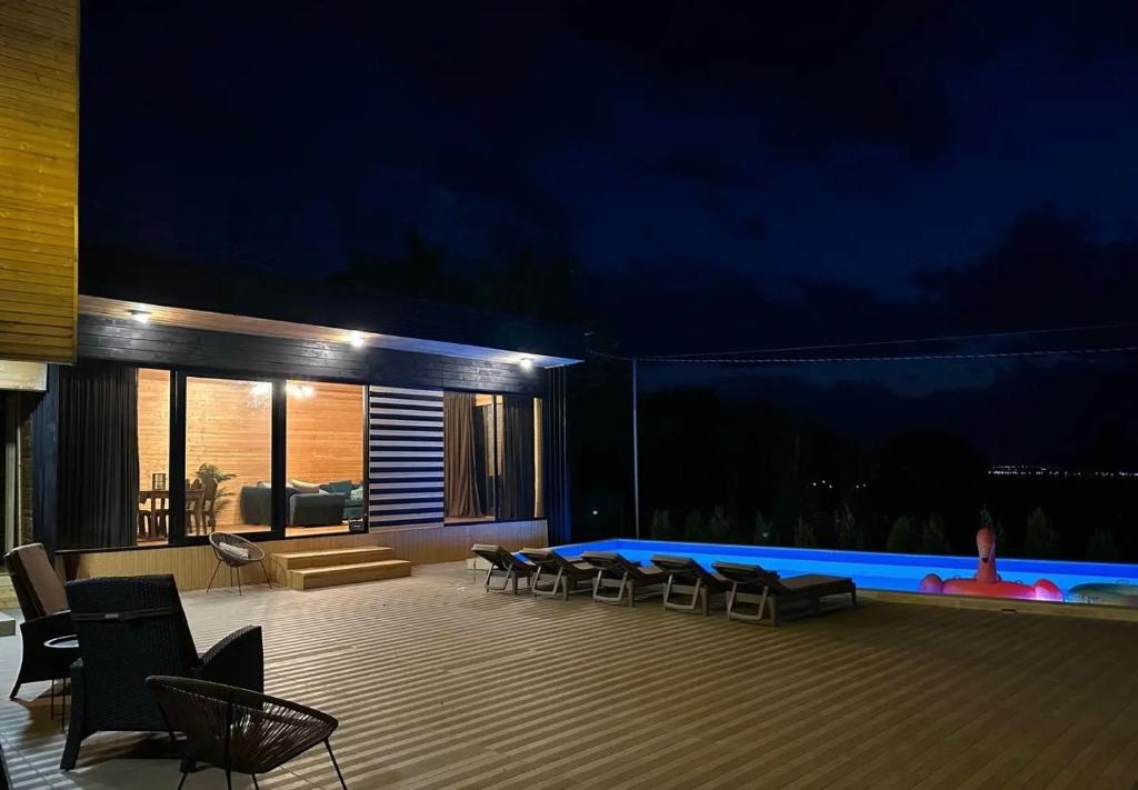 un patio con sillas y una piscina por la noche en saguramo agaraki, en Saguramo