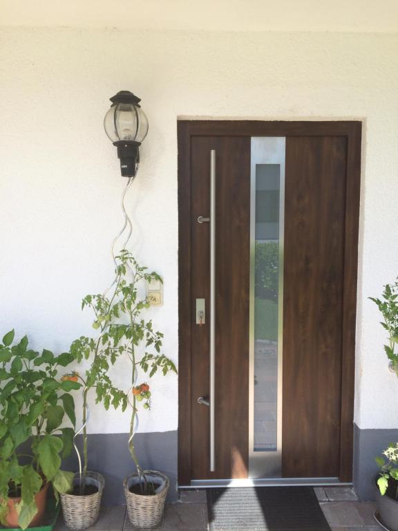 une porte en bois éclairée à côté de certaines plantes dans l'établissement L&L Lodge Günding, à Günding