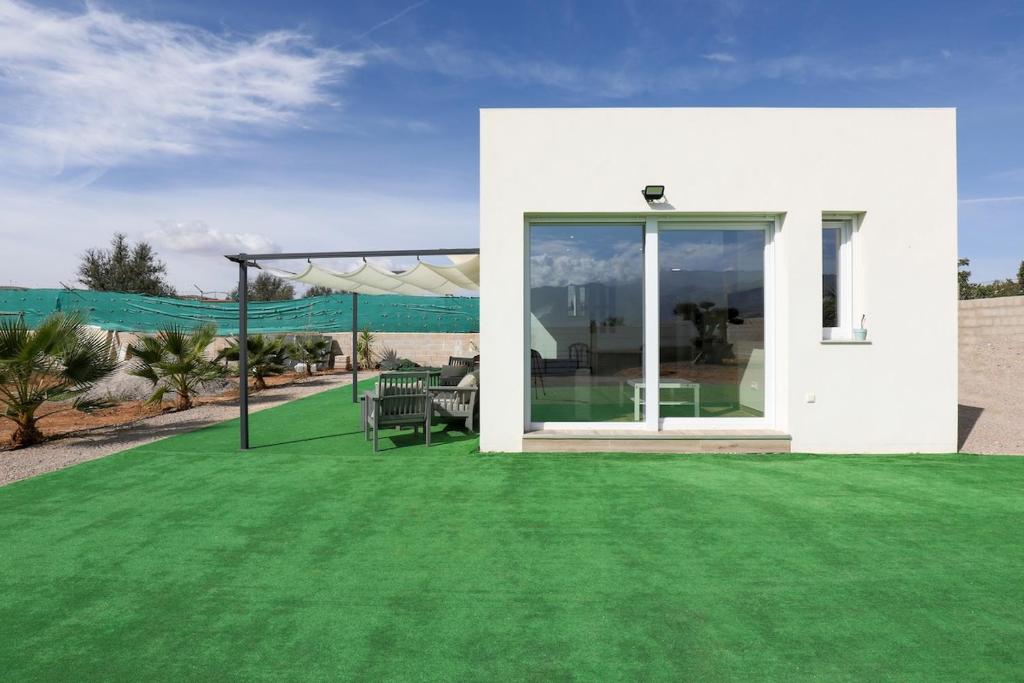 a white house with a green lawn with a patio at EyA House in Padul