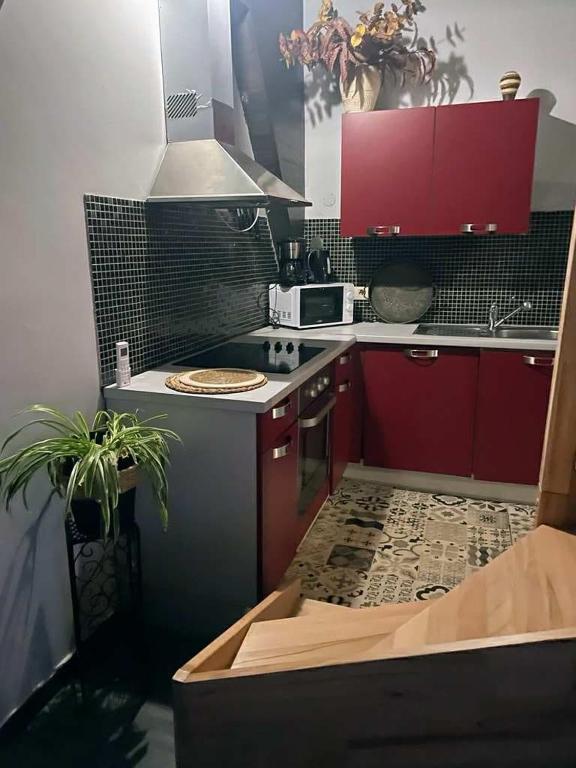 La cuisine est équipée de placards rouges et d'un four avec plaques de cuisson. dans l'établissement Le petit calme, à Frameries