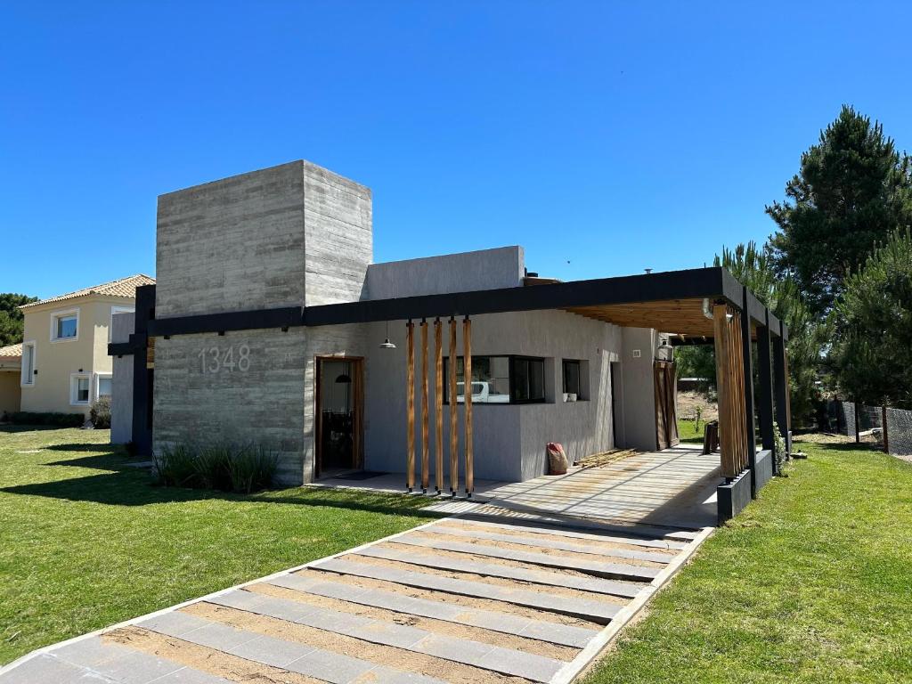 une maison moderne avec une terrasse en bois dans une cour dans l'établissement Casa Moderna, Barrio Nayades, à Pinamar
