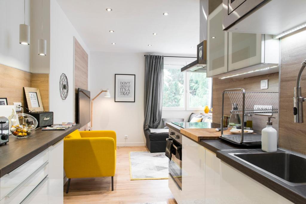 une cuisine avec des placards blancs et une chaise jaune dans l'établissement Unsejouranantes - Le Magellan, à Nantes