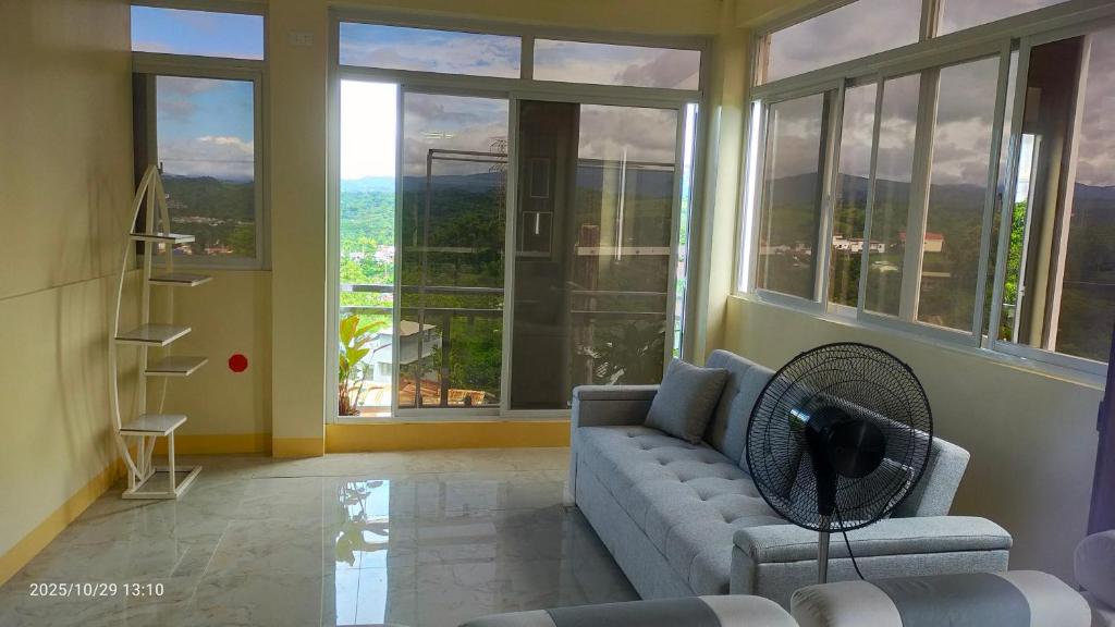 a living room with a couch and large windows at J Jireh Residences in San Jose del Monte