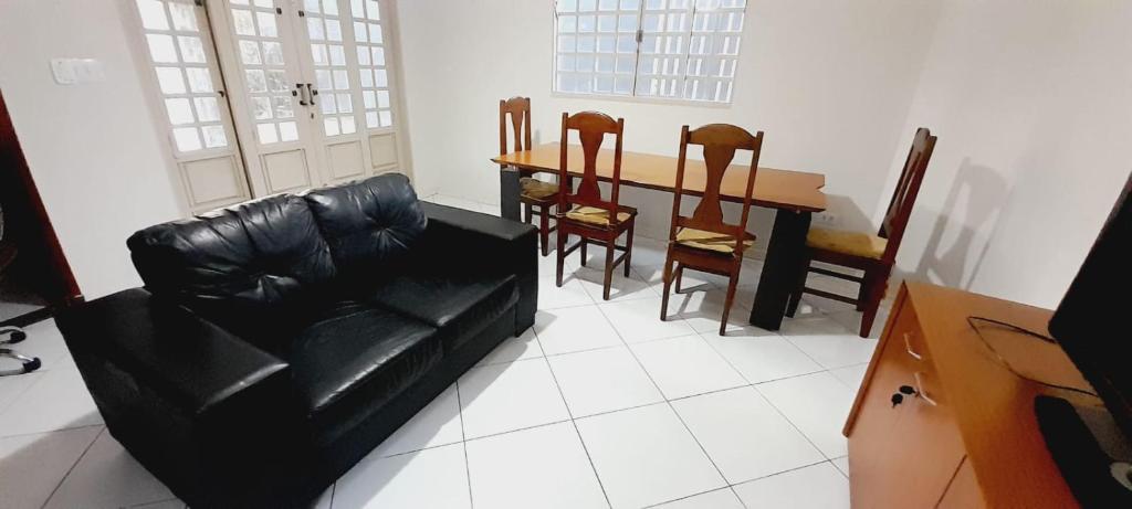 a living room with a black leather couch and a table at bairro Amambai - sobrado com 5 quartos e 5 banheiros in Campo Grande