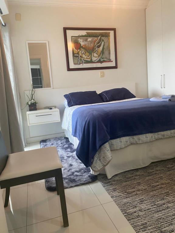 a bedroom with a bed with a blue comforter at Suite Anthony Aconchegante in Xanxerê