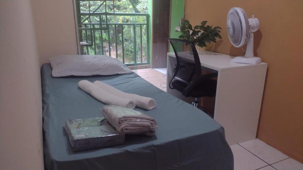 a room with a bed with a desk and a fan at Quarto para cop30 em casa de família in Belém
