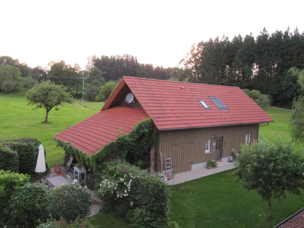 una pequeña casa con techo rojo en un campo verde en Claudis Ferienhäusle, en Amtzell
